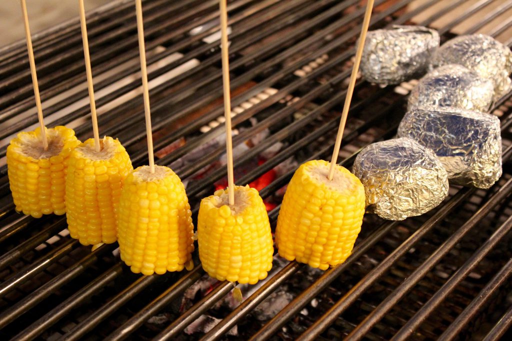 Gegrillte Maiskolben isst man am besten mit einem Maiskolbenhalter. Zur Not geht auch ein Holzspieß.
