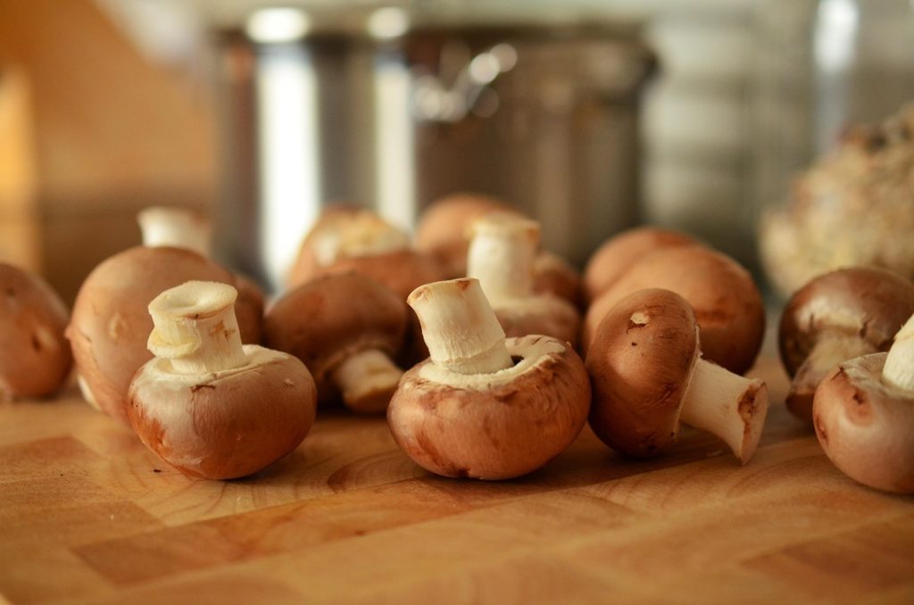 Frische braune Champignons mit Stielen auf einem Holzbrett