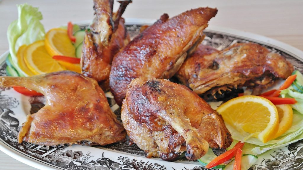 Zerlegte Ente mit knuspriger, goldbrauner Haut auf einer Platte, angerichtet mit Orangenscheiben und Salat