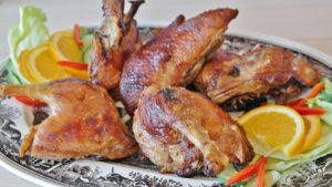 Zerlegte Ente mit knuspriger, goldbrauner Haut auf einer Platte, angerichtet mit Orangenscheiben und Salat