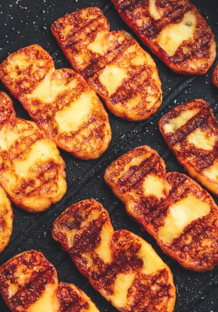 Scheiben gegrillten Halloumis mit deutlichen Grillstreifen auf einer Grillplatte