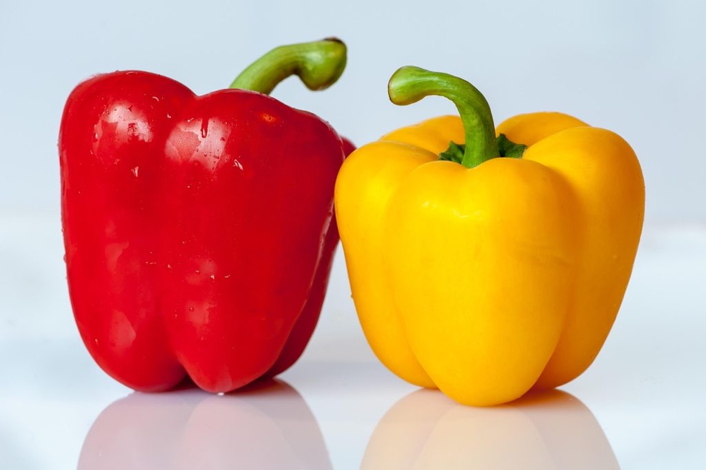 Eine rote und eine gelbe Gemüsepaprika nebeneinander