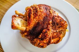 Gegrillte Schweinshaxe mit knuspriger Schwarte auf einem weißen Teller
